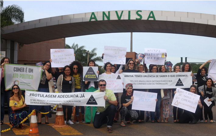 Members of the Alliance for an Adequate and Healthy Diet, a civil society coalition in Brazil, push Brazil’s National Health Surveillance Agency to approve food warning labels.