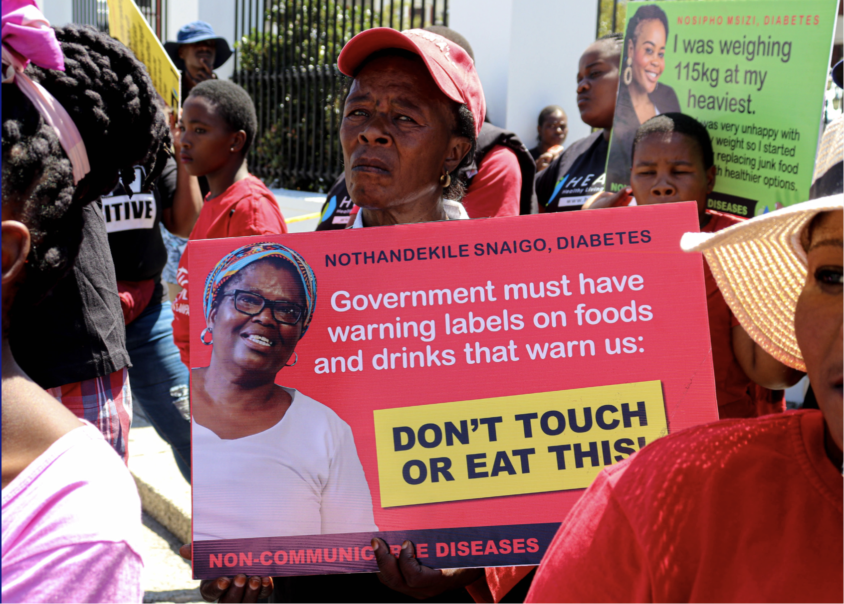A woman holds a protest sign to denounce food and beverage industry interference and encourage government action on food policies.